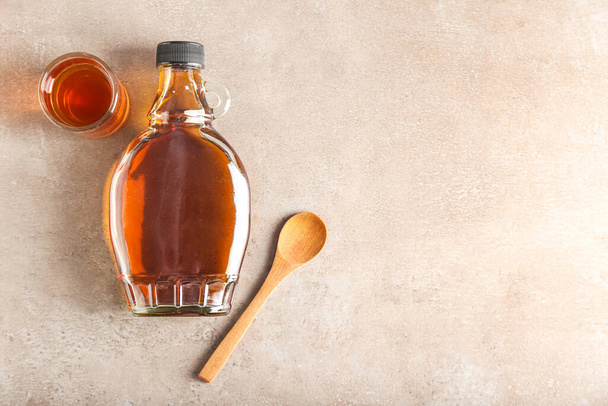 Bottle and glass of maple syrup on light background - Photo, image