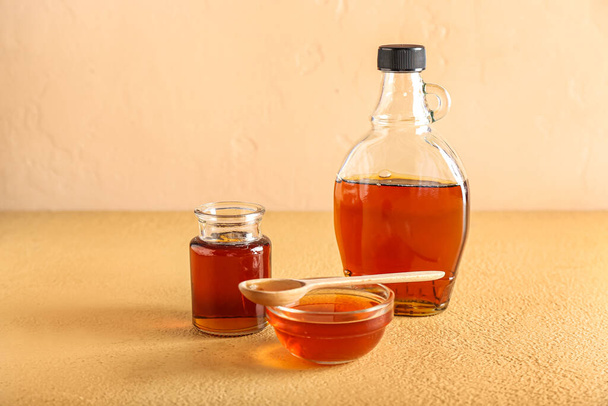 Bottles and bowl of maple syrup on color background - Foto, Imagem