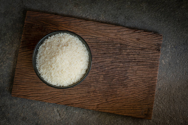 Healthy food. Thai jasmine rice, raw rice in a black bowl above an old wooden plank. Top view, copy space, high-resolution product., still life Thai food top view - Fotoğraf, Görsel