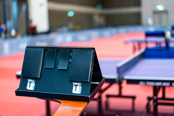A tennis table black scoreboard is placed next to the table tennis table for referee count the score, which acts as a blurred background of pingpong tournament. - Photo, image
