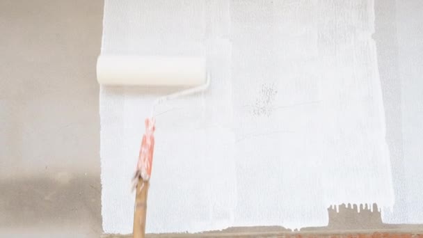 Χέρι με ρολό μπογιάς κινείται στον τοίχο. Roller Ζωγραφική γκρίζο τοίχο με λευκό χρώμα. Αντίληψη ανακαίνισης κατοικίας - Πλάνα, βίντεο