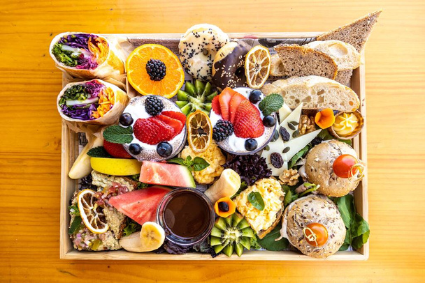 A top view of assorted fruits, cheese, bread, and dessert on a platter - Φωτογραφία, εικόνα