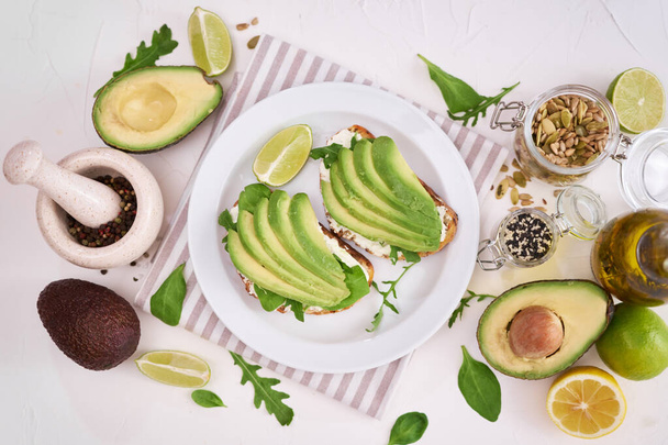 Freshly made Avocado and cream cheese toasts on a white ceramic plate and ingredients. - Foto, immagini