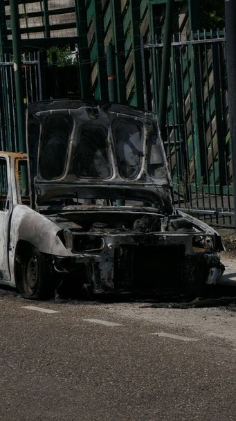 A vertical shot of an abandoned burnt car on the roadside - Foto, immagini