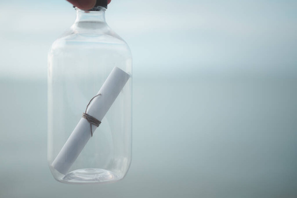 Bottle with message inside on sea and sky background, close-up - Fotó, kép