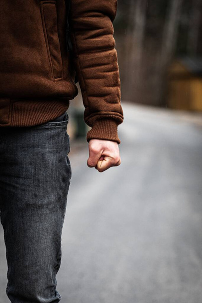 A vertical closeup shot of an angry man with a tightened fist in the street - Photo, Image