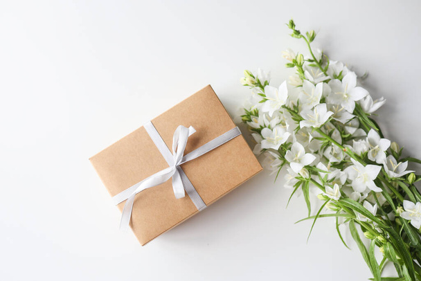 Cardboard gift box with a bow and flowers on a white background - Фото, зображення