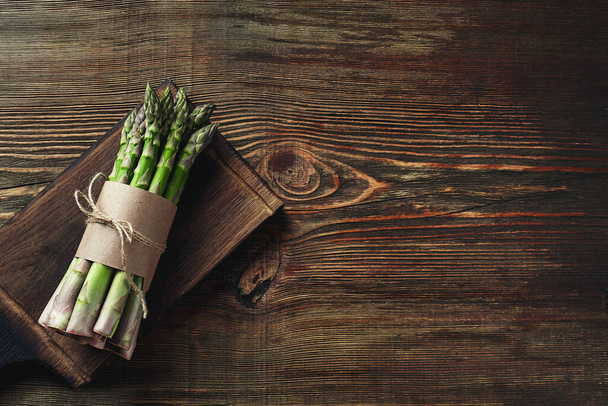 Bunch of an edible, juicy sprouts of asparagus on wooden background. Fresh, green vegetables, top view. Healthy food. Fall harvest, agricultural farming concept. - Foto, Imagem
