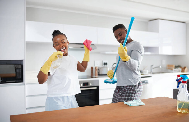 Διαίρει και βασίλευε. ένα ευτυχισμένο νεαρό ζευγάρι που διασκεδάζει καθαρίζοντας την κουζίνα στο σπίτι - Φωτογραφία, εικόνα