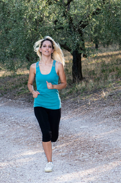running blonde girl jogging outdoors on country road - Foto, Imagen