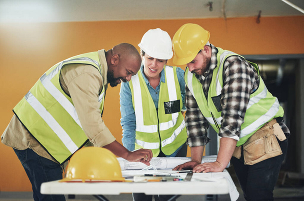 The right plan is a firm foundation for success. a group of builders going over building plans at a construction site - Valokuva, kuva