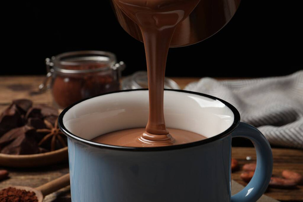 Pouring yummy hot chocolate into mug on table, closeup - Foto, imagen
