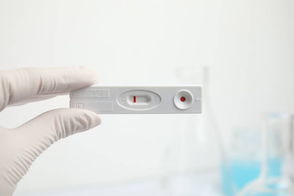 Doctor holding disposable express test for hepatitis indoors, closeup - 写真・画像
