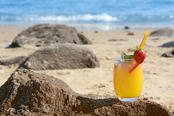 Glass of refreshing drink with strawberry on beach near sea, space for text - Foto, Imagem