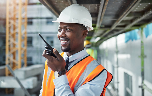 Communication carries a project from inception to completion. a young man using a walkie talkie while working at a construction site - Foto, immagini