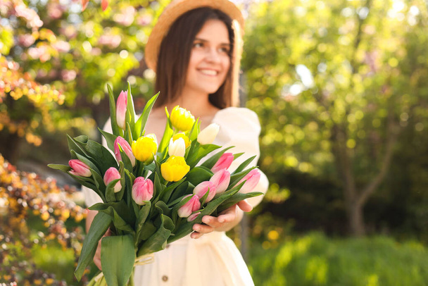 Beautiful young woman with bouquet of tulips in park, focus on flowers. Space for text - Φωτογραφία, εικόνα