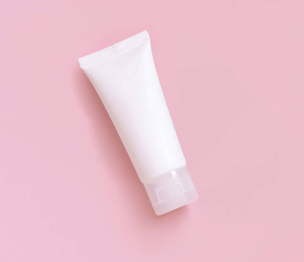 White plastic cream tube on light pink,top view, cosmetic mockup. Skincare beauty product, cream or lotion. Exotic natural cosmetics, pastel minimal compositio - Fotografie, Obrázek