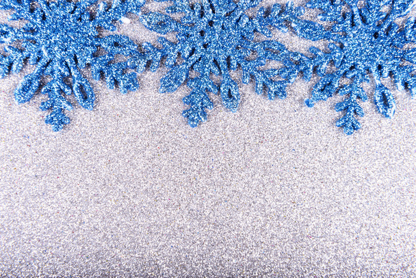 Сині сніжинки на фоні срібних блискіток
 - Фото, зображення