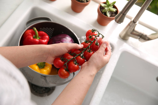 Woman washing fresh cherry tomatoes in kitchen sink, closeup - Photo, image