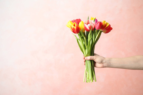 Woman holding beautiful spring tulips on light pink background, closeup. Space for text - Fotoğraf, Görsel