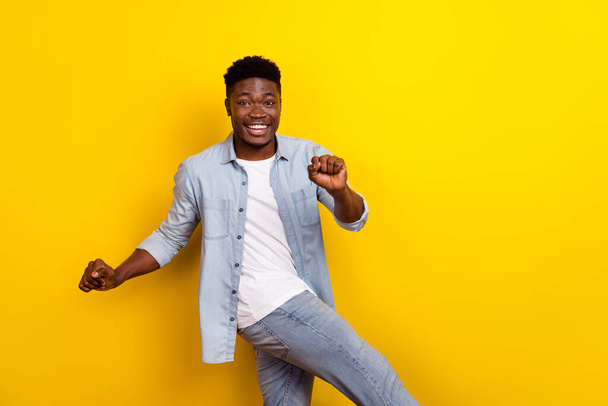 Photo of funny millennial brunet guy dance wear jeans shirt isolated on yellow color background. - 写真・画像