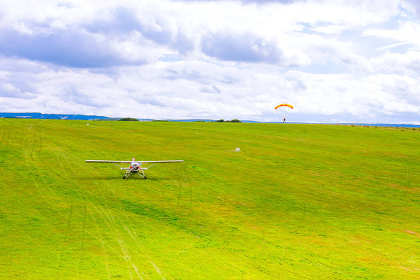 Small plane on a green field, paratrooper landing on a green field. Air entertainment. View from above. - Foto, afbeelding