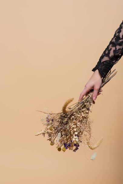 Cropped view of woman holding dry flowers isolated on beige  - Фото, зображення