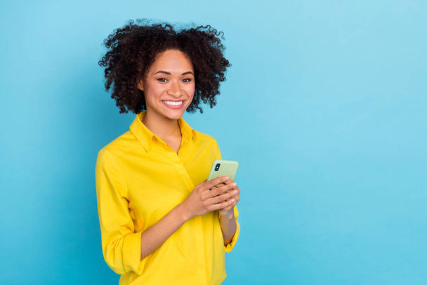 Portrait of cheerful pretty lady hold telephone empty space wear smart casual isolated on blue color background. - 写真・画像