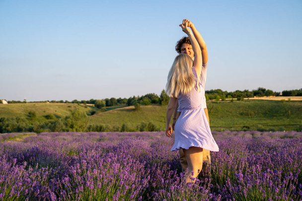 romantic couple in purple matching outfit in love dancing together in lavender field - Foto, afbeelding