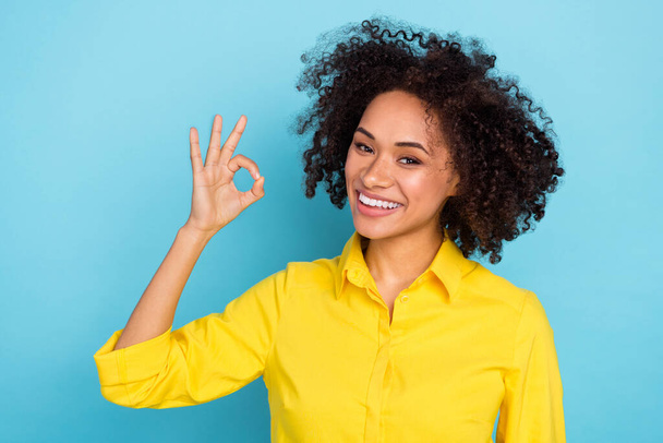 Photo of hooray curly hairdo young lady show okey wear yellow blouse isolated on blue color background. - Foto, immagini