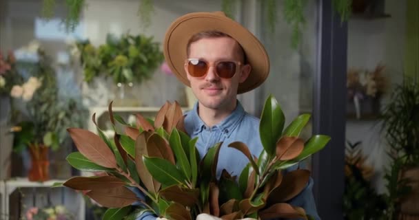 Mothers Day, Valentines Day or International Womens Day concept. Smiling hipster male person in sunglasses and hat with fresh spring flower bouquet and welsh corgi dog. High quality 4k video - 映像、動画