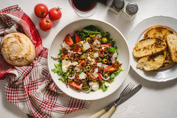 Tasty dried tomatoes salad with fresh vegetables mix and mozzarella cheese served with toast. Healthy food concept. Top view, flat lay - Fotoğraf, Görsel