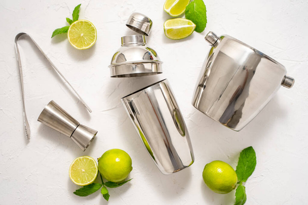 Top view of Bartenders coctail tools set. Steel shaker, measure, pliers with lime. Drink concept. Flat lay - Photo, Image
