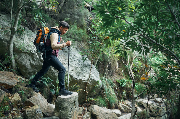 Go wild for a while. a young man using a walking pole while hiking through the mountains - Photo, Image