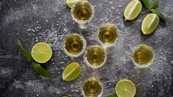 Top view of Golden Tequila shots served with lime and sea salt on table, flat lay. - Video, Çekim