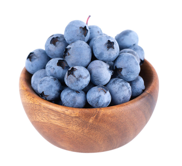 Fresh blueberry in wooden bowl, isolated on white background. Bilberry or whortleberry. Clipping path - Фото, изображение