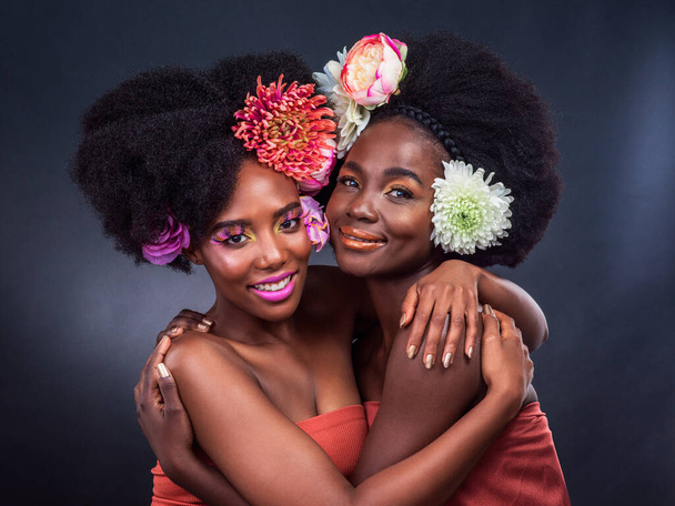 Αυτό που είναι στην καρδιά μας κάνει όμορφους. δύο όμορφες γυναίκες ποζάρουν μαζί με λουλούδια στα μαλλιά τους - Φωτογραφία, εικόνα