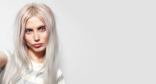 Στούντιο γκρο πλαν πορτρέτο του αστείο όμορφο κορίτσι με ξανθά μαλλιά σε λευκό φόντο με αντίγραφο χώρου, πανοραμική πανό. - Φωτογραφία, εικόνα