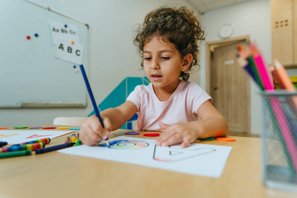 English lesson at elementary school or kindergarten. Girl learning the alphabet and colors coloring the letter A. Selective focus. - Fotoğraf, Görsel