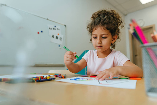 English lesson at elementary school or kindergarten. Girl learning the alphabet and colors coloring the letter A. Selective focus. - Foto, Imagem