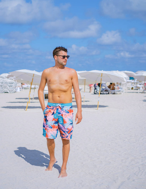 Miami beach, young men on the beach, lifeguard hut Miami beach Florida. caucasian men on the beach during sunset. European men shirtless with swim short - Fotografie, Obrázek