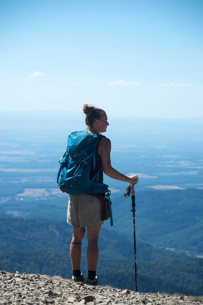 Le grand Ballon - France - 4 August  2022 - Portrait on back view of woman standing at the top of the mountain with sticks and backpack  - 写真・画像