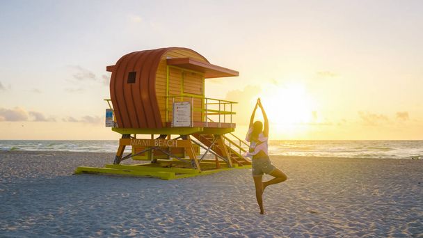 Miami Beach, a couple on the beach at Miami Florida, lifeguard hut Miami Asian women and caucasian men on the beach during sunset. Woman watching sunset on the beach - 写真・画像