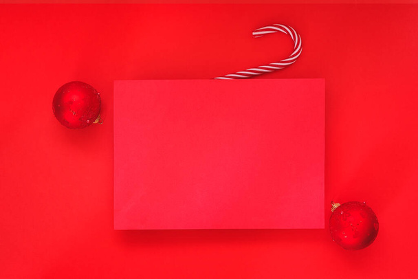 Empty red background and blank Christmas paper sheet with red baubles on red background. Minimal concept. Advertising template. Top view, place for text - Fotografie, Obrázek