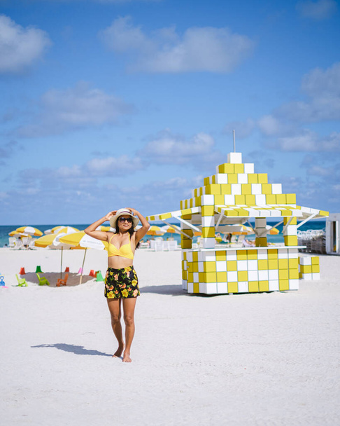 Маямі-Біч, подружжя на пляжі в Маямі-Флориді, жінки-рятувальники з Маямі-Азіатської Азії та чоловіки-ізгої на пляжі під час заходу сонця. Щасливі жінки йдуть по білому пляжу. - Фото, зображення
