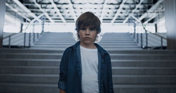 Üzgün çocuk suratlı kamera mutsuz bir şekilde kapanıyor. Depresyondaki okul çocuğu boş merdivenlerde tek başına dikiliyor. Sınıfın zorbalığından sonra umutsuzluğa kapılmış küçük dışlanmış biri. Okul konseptinde yalnızlık. - Fotoğraf, Görsel