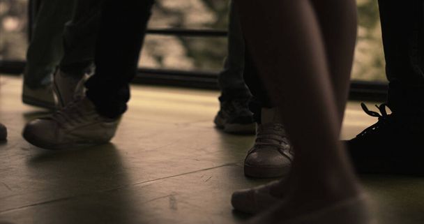 Closeup children legs standing group on hall floor. Diverse bullies pushing outcast. Unrecognized aggressive teenagers hurting punching classmate in school corridor. Adolescent violence problem. - Photo, Image