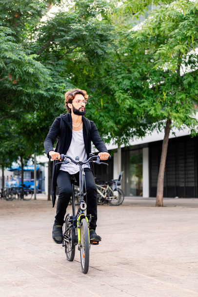 stylish young man riding his bike through the city, urban lifestyle and sustainable mobility concept, copy space for text - Photo, Image