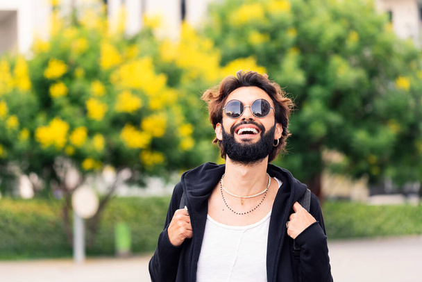 stylish young student with beard and sunglasses laughing happy looking at camera, concept of youth and urban life style, copy space for text - Foto, Bild
