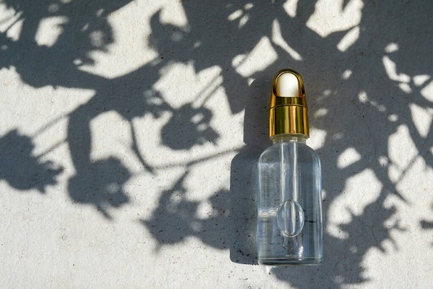 Dropper glass Bottle Mock-Up with leaves shadows on concrete background. Body treatment and spa. Natural beauty products. Eco cream, serum, skin care blank bottle. Anti-cellulite massage oil - Foto, afbeelding